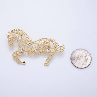 Gold horse-shaped brooch with rhinestones next to a quarter for scale on a light gray background