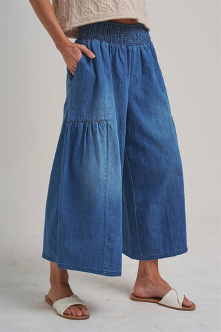 Person wearing blue denim wide-leg pants on a plain background