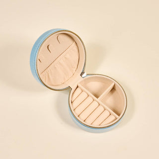 Round jewelry case with blue exterior and beige interior on a beige background