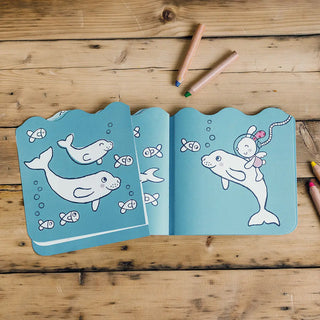 Open coloring book with whale illustrations on a wooden surface