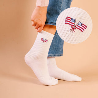 White socks with American flag design worn by a person on a beige background
