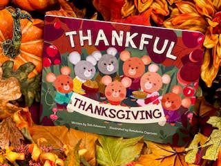 Children's book titled 'Thankful Thanksgiving' surrounded by autumn leaves and pumpkins.