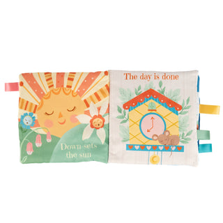 A baby activity book with two soft fabric pages. The left page shows a smiling sun with rays and the text 'Down sets the sun,' with colorful flower tabs on the right side.