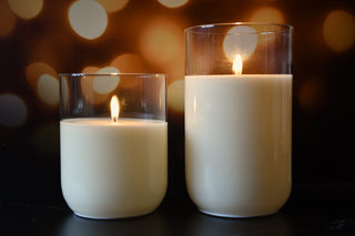 Two lit candles in glass holders with a blurred bokeh background