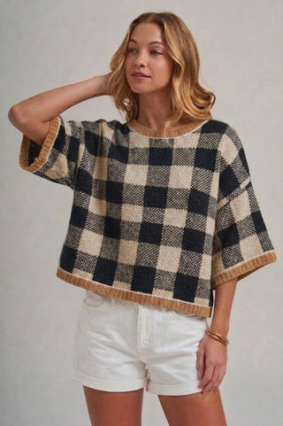 Woman wearing a black and white checkered poncho with a plain background