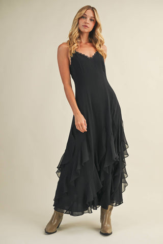 Woman wearing a black dress with ruffled layers on a beige background
