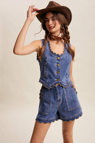 Woman wearing a denim romper and brown hat on a beige background