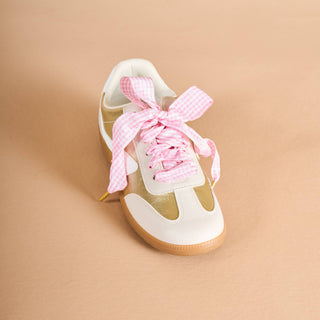 White sneaker with pink laces on a beige background