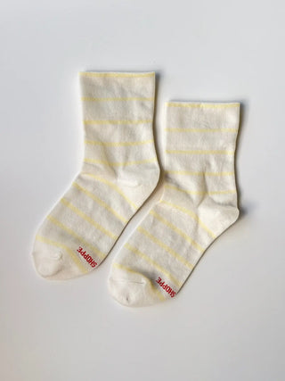 Pair of white socks with yellow stripes on a light gray background