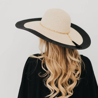 Person wearing a beige hat with a black rim on a plain background