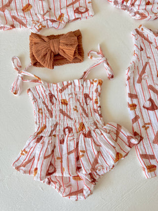 Baby romper with ruffles and a matching headband on a light background