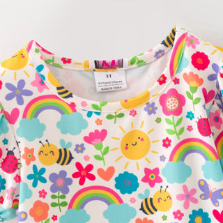 Children's clothing with colorful patterns of flowers, rainbows, and bees on a white background.