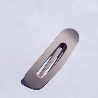 Beige hair clip on a light purple background