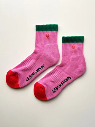 Pink socks with green cuffs and red toes, featuring a heart design and 'Le Bon Shoppe' branding on a light background.