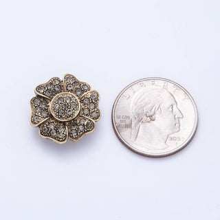 Gold floral brooch with gemstones next to a U.S. quarter on a white background