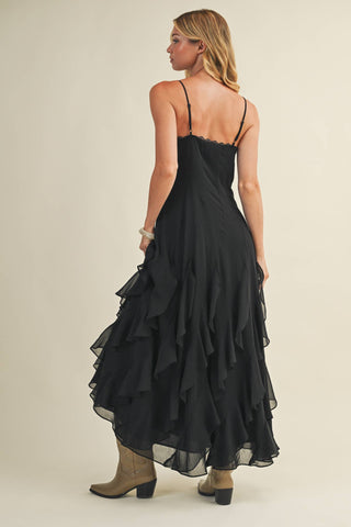 Woman wearing a black ruffled dress on a plain background