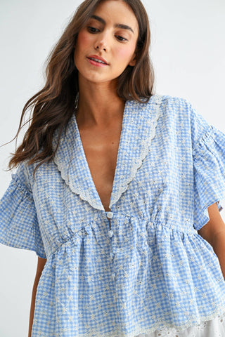 Woman wearing a blue checkered dress with lace details against a white background