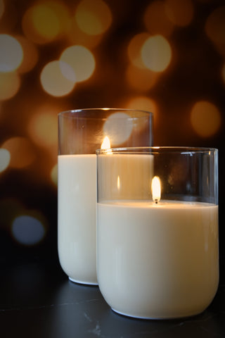 Two lit candles in glass holders with a blurred bokeh background