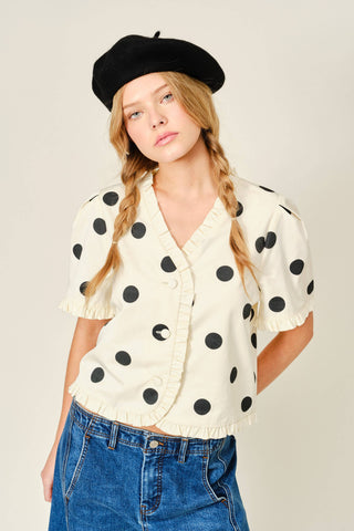 Woman wearing a polka dot blouse and beret on a plain background
