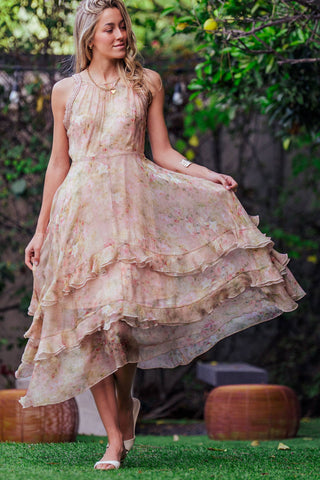 Woman in a floral dress standing outdoors with greenery in the background