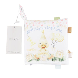 Baby book with 'Birthday on the Farm' text and duckling illustration, featuring the brand 'ali+ali'.