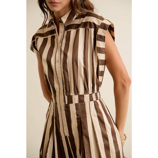 Woman wearing a brown and beige striped dress against a neutral background