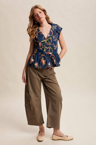 Woman wearing a floral top and brown pants on a beige background