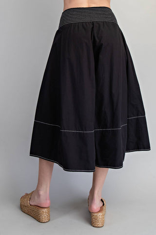 Black skirt with striped waistband worn by a person on a gray background