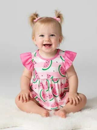 Baby wearing a pink watermelon print romper sitting on a white surface.