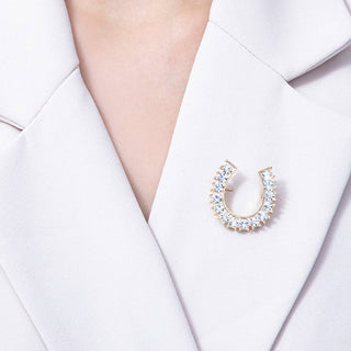 Horseshoe-shaped brooch with crystals on a white blazer