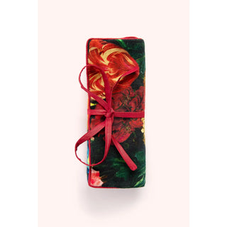 Floral-patterned jewelry roll wrapped with a red ribbon on a white background