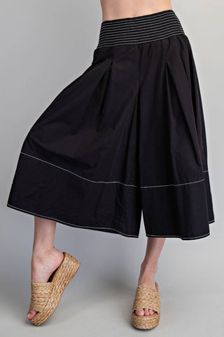 Black skirt with striped waistband worn by a person on a gray background