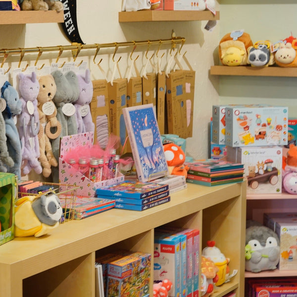 Toy store display with plush toys, books, and educational items on shelves.