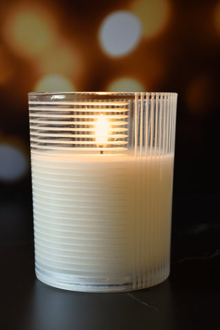 Candle in a textured glass holder with a blurred bokeh background