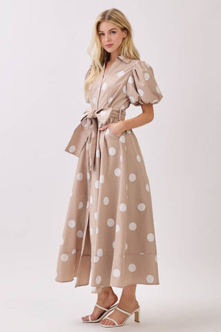 Woman wearing a beige dress with white polka dots on a white background