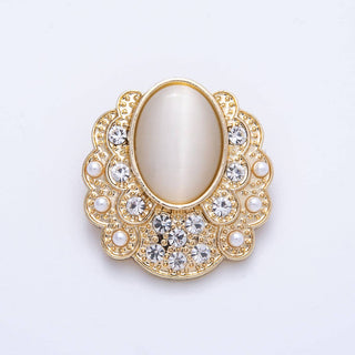Decorative brooch with gold frame, pearl center, and crystal accents on a light gray background