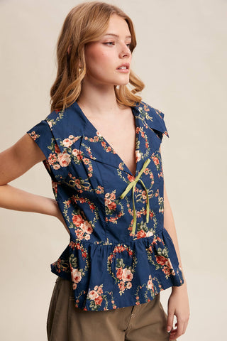 Woman wearing a floral peplum top against a beige background