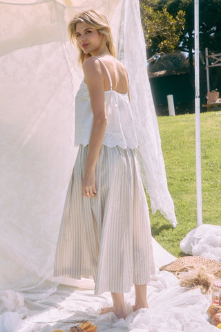 Woman in a white dress standing outdoors with greenery in the background