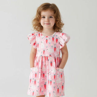 Young girl wearing a pink dress with animal print on a plain background