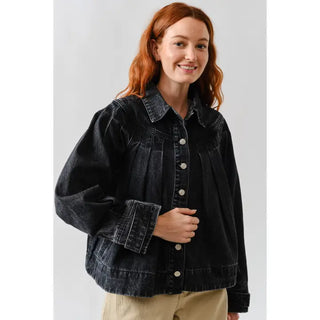 Woman wearing a black denim jacket against a white background