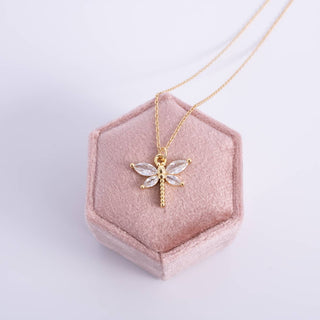 Gold necklace with a dragonfly pendant on a pink jewelry box