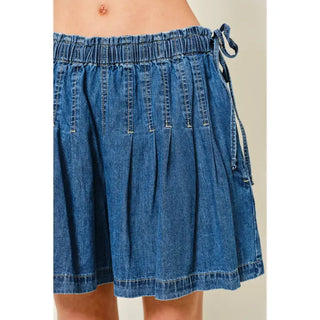 Blue denim skirt worn by a person on a plain background