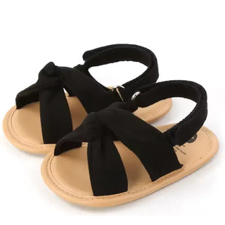 Pair of black sandals with tan soles on a white background
