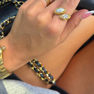 Close-up of a hand wearing gold jewelry including rings and a bracelet.