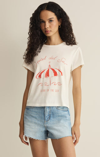 Woman wearing a white t-shirt with red graphics and text, standing against a plain background