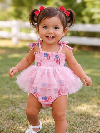 Child wearing a pink outfit with American flag patterns outdoors.