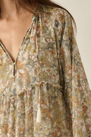 Close-up of a woman wearing a long-sleeve bohemian floral print dress with a tie-neck and tassel detail.