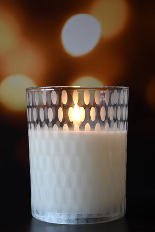 Candle in a glass holder with a patterned base against a blurred background