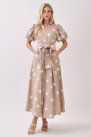 Woman wearing a beige dress with white polka dots on a white background