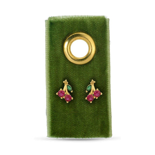 Gold earrings with red and green stones on a green velvet card